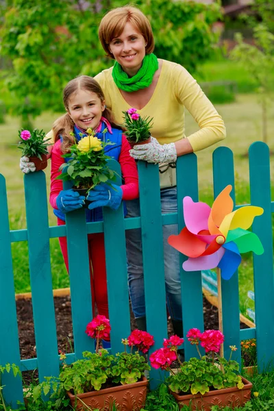 Gardening - lovely girl with mother working in flowers garden — Stock Photo, Image