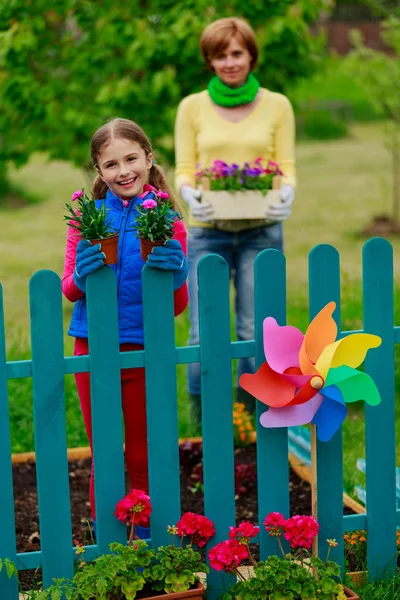 Giardinaggio - bella ragazza con madre che lavora in giardino di fiori — Foto Stock