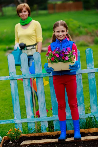 Jardinage - belle fille avec mère travaillant dans le jardin de fleurs — Photo