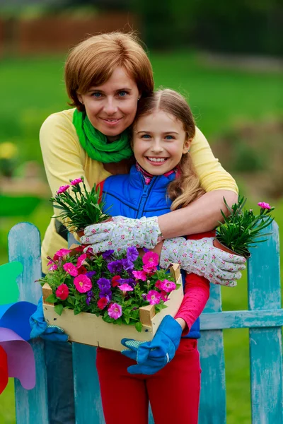 Trädgårdsskötsel - härlig tjej med mor arbetar i blommor trädgård — Stockfoto