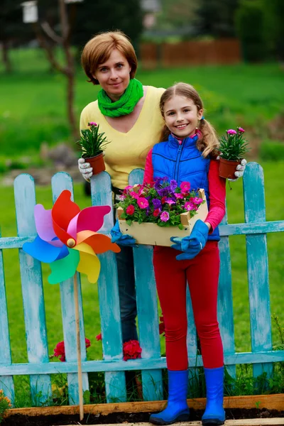 Gardening - lovely girl with mother working in flowers garden — Stock Photo, Image