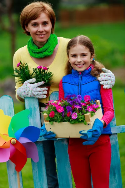 Jardinería - chica encantadora con la madre trabajando en el jardín de flores — Foto de Stock
