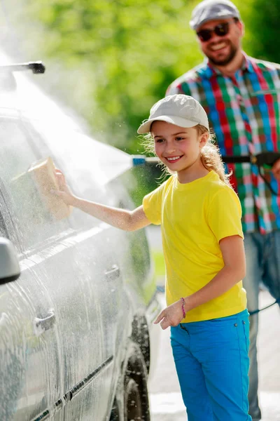 Myjnia - młoda dziewczyna pomoc ojca do mycia samochodu — Zdjęcie stockowe