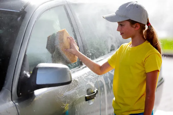 Lavado de coches - una adolescente lava el coche — Foto de Stock