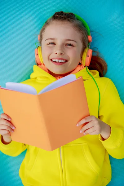 Young girl with headphones reading a book — Stock Photo, Image