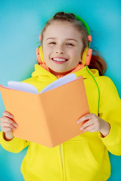 Young girl with headphones reading a book — Stock Photo, Image