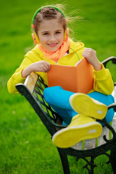 Young girl with headphones reading a book — Stock Photo, Image