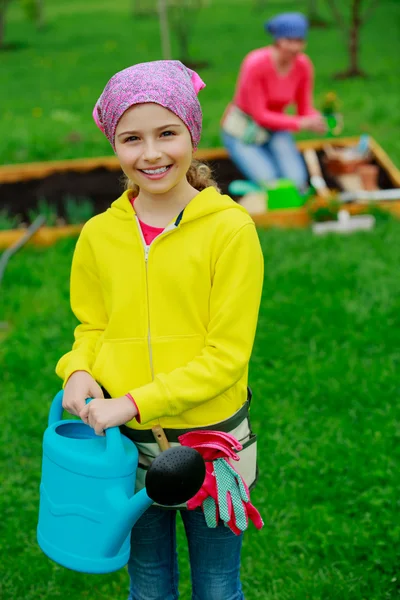 Gardening - girl helping mother in the garden — Stock Photo, Image