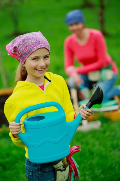 Jardinería - niña ayudando a la madre en el jardín — Foto de Stock