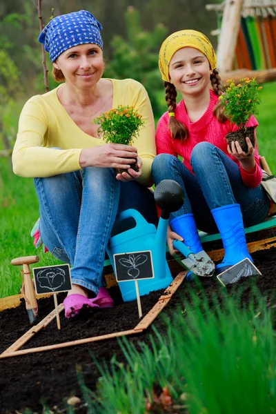 Gärtnern, Pflanzen - Mädchen hilft Mutter im Garten — Stockfoto
