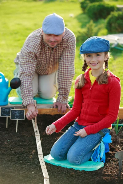 Trädgårdsskötsel, plantering - ung flicka att hjälpa pappa i trädgården — Stockfoto