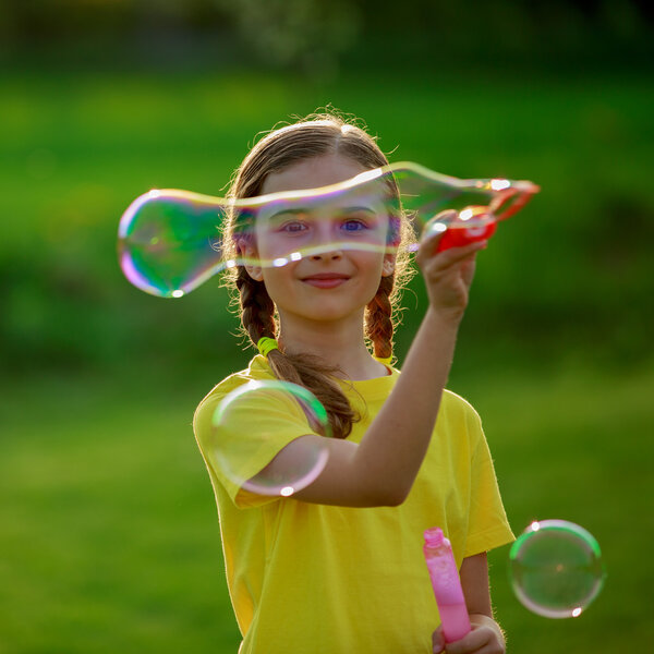 Summer joy, young girl playing with soap bubbles