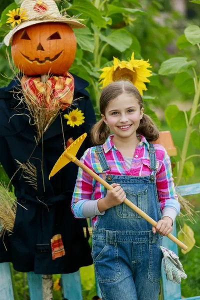 Scarecrow and happy girl  in the garden — Stock Photo, Image