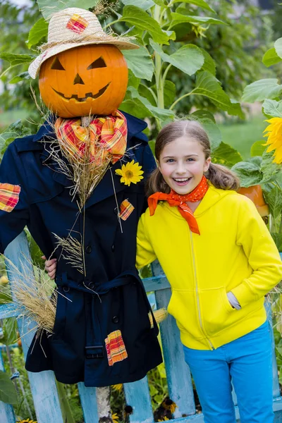 Halloween, Fågelskrämman och glad tjej i trädgården — Stockfoto