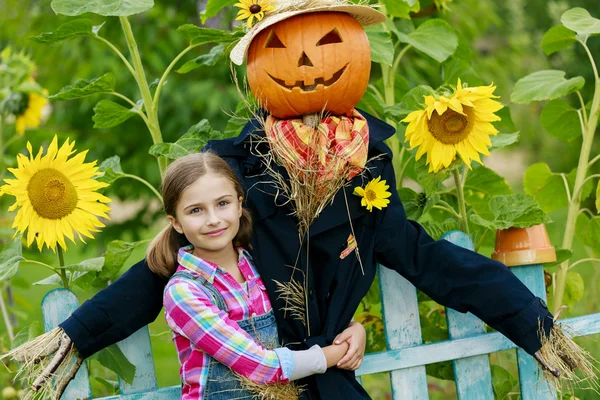 Scarecrow and happy girl  in the garden — Stock Photo, Image