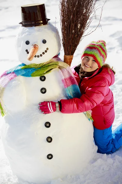 Winter fun, happy kid playing with snowman — Stock Photo, Image