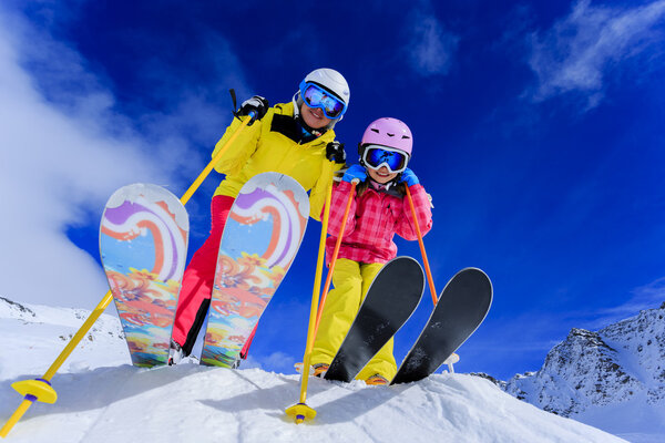 Skiing, skiers, sun and fun - family enyoing winter vacation