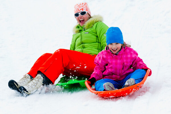 Winter playing, fun, snow and family sledding at winter time