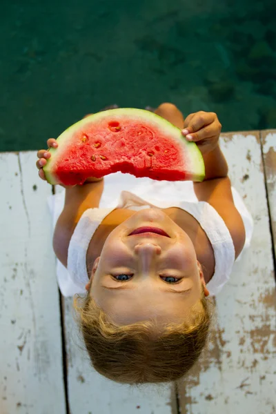 Summer joy, lovely girl eating fresh armelon on the beach — стоковое фото