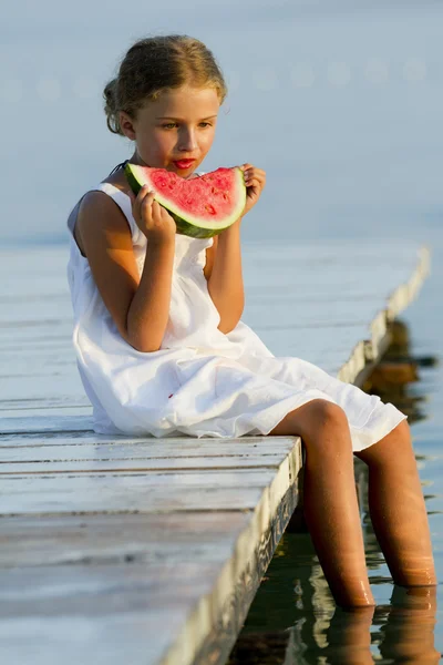 Summer joy, lovely girl eating fresh armelon on the beach — стоковое фото