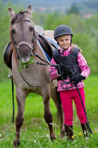 小さな女の子が牧草地に馬を放牧馬と騎手- — ストック写真