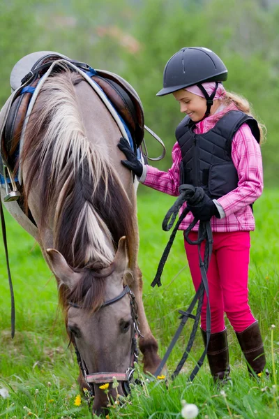 Koń i dżokej - mała dziewczynka jest wypas konia na łące — Zdjęcie stockowe