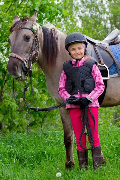 小さな女の子が牧草地に馬を放牧馬と騎手- — ストック写真