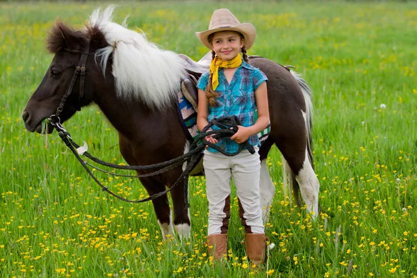 小さな女の子が牧草地に馬を放牧馬と騎手- — ストック写真