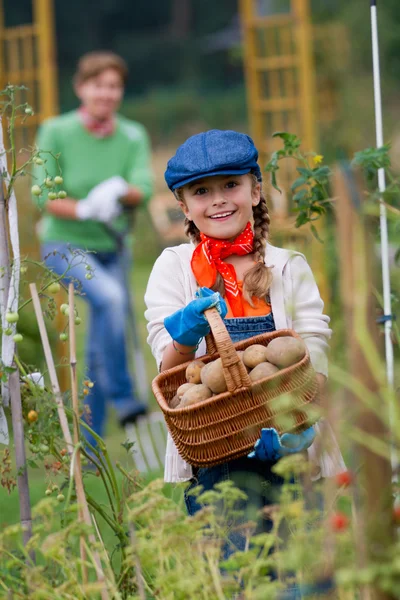 Gartenarbeit - hübsches Mädchen mit Mutter, die im Gemüsegarten arbeitet — Stockfoto