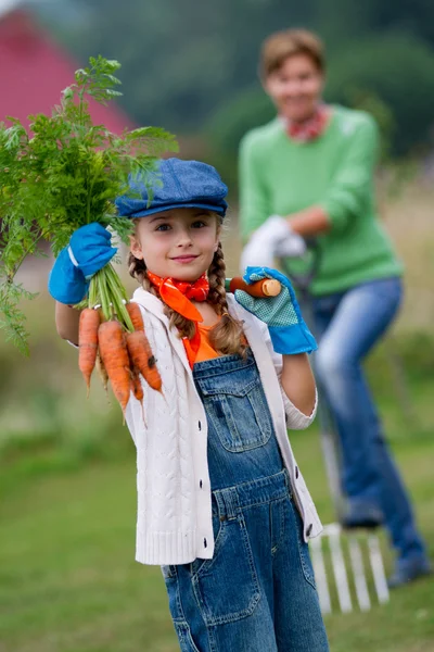 Gartenarbeit - hübsches Mädchen mit Mutter, die im Gemüsegarten arbeitet — Stockfoto