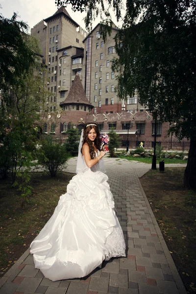 Felice sposa nel parco estivo su sfondo palazzo — Foto Stock