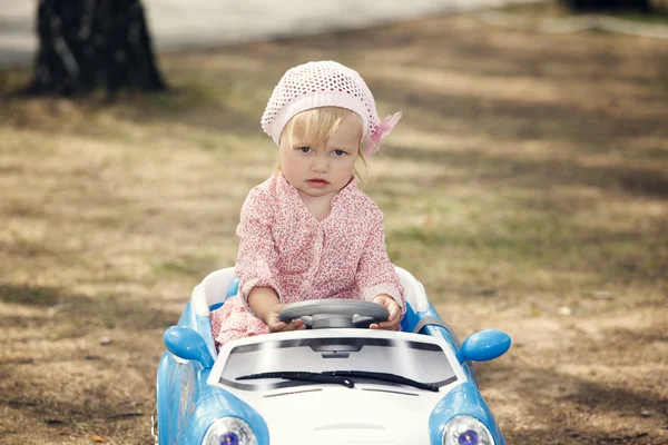 Улыбающаяся маленькая девочка управляет электромобилем — стоковое фото