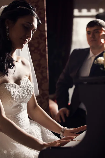 Recém-casados. Noiva tocando piano — Fotografia de Stock