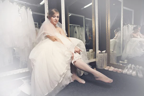 Bride dresses stockings on feet — Stock Photo, Image