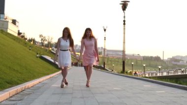 iki kız arkadaş elele bir kaldırımda atlama