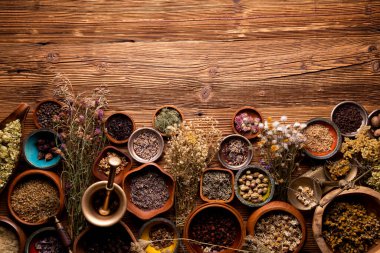 Doğal tıp geçmişi. Kâselerde çeşitli kuru otlar ve rustik ahşap masa üzerinde pirinç havan..