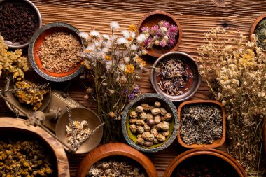 Doğal tıp geçmişi. Kâselerde çeşitli kuru otlar ve rustik ahşap masa üzerinde pirinç havan..