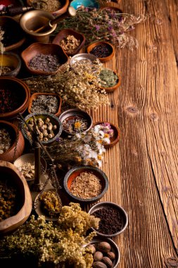 Doğal tıp geçmişi. Kâselerde çeşitli kuru otlar ve rustik ahşap masa üzerinde pirinç havan..