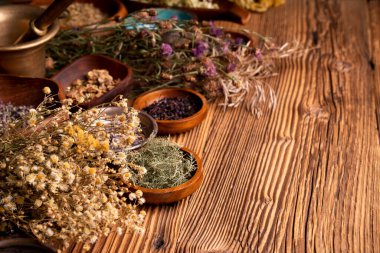 Doğal tıp geçmişi. Kâselerde çeşitli kuru otlar ve rustik ahşap masa üzerinde pirinç havan..