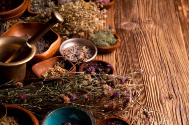 Doğal tıp geçmişi. Kâselerde çeşitli kuru otlar ve rustik ahşap masa üzerinde pirinç havan..