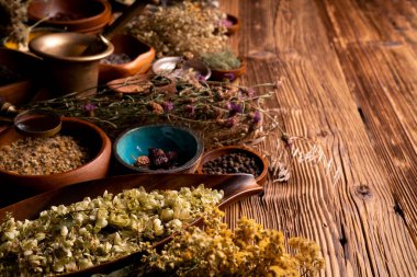 Doğal tıp geçmişi. Kâselerde çeşitli kuru otlar ve rustik ahşap masa üzerinde pirinç havan..