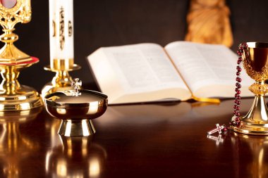 Katolik sembolleri kompozisyonu. Din kavramı. İsa figürü, Haç, Monstrance, Kutsal İncil ve gri arka planda altın kadeh.. 