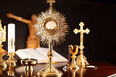 Katolik sembolleri kompozisyonu. Din kavramı. İsa figürü, Haç, Monstrance, Kutsal İncil ve gri arka planda altın kadeh.. 