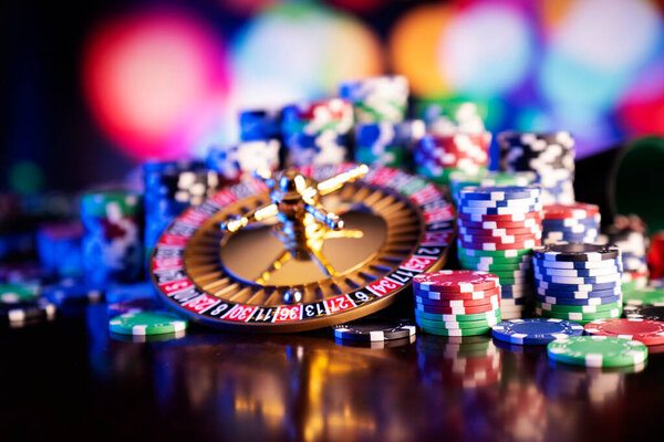 Casino theme.  Roulette wheel, poker chips and dice on  colorful bokeh background.