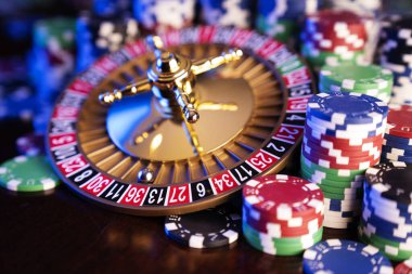 Kumarhane teması. Renkli arkaplanda rulet çarkı ve poker çipleri.