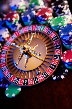 Kumarhane teması. Renkli arkaplanda rulet çarkı ve poker çipleri.