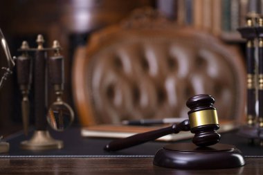 Yargıç ofisi. Gavel, tartı, masadaki heykel. Kitaplıkta hukuk kitapları var..