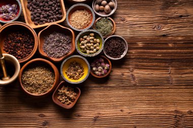 Doğal tıp geçmişi. Kâselerde çeşitli kuru otlar ve rustik ahşap masa üzerinde pirinç havan..