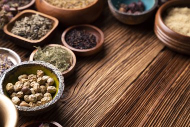 Doğal tıp geçmişi. Kâselerde çeşitli kuru otlar ve rustik ahşap masa üzerinde pirinç havan..