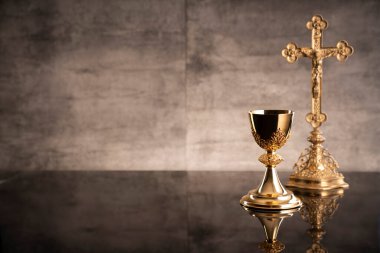 Katolik dini kavramı. Katolik sembolleri kompozisyonu. Haç, Monstrance, Kutsal İncil ve altın kadeh ahşap sunak ve gri arka plan. 